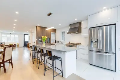 a kitchen with white cabinets and a large island with bar stools at Toronto Midtown Home Suites in Toronto