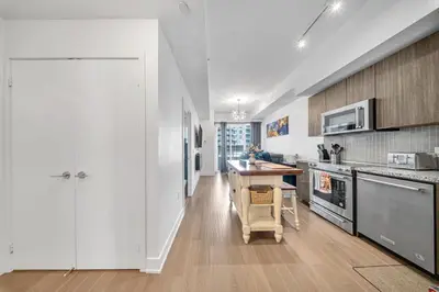 a kitchen with white cabinets and a table in it at Modern Condo with Balcony, Gym and Free Parking in Toronto