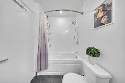 a white bathroom with a tub and a toilet at Modern Condo with Balcony, Gym and Free Parking in Toronto