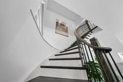 a staircase with a wooden rail and a picture on the wall at Hidden 3BR Gem with Workspace, Fast wifi and Parking in Toronto