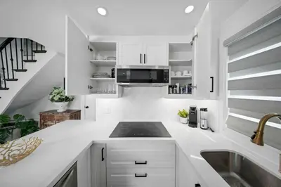 a white kitchen with a sink and a stove at Hidden 3BR Gem with Workspace, Fast wifi and Parking in Toronto