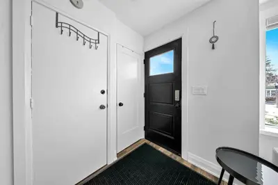 a hallway with a black door and a black chair at Hidden 3BR Gem with Workspace, Fast wifi and Parking in Toronto