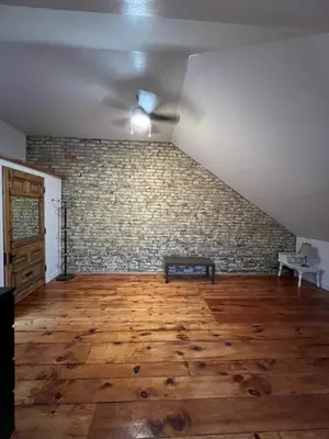an empty room with a ceiling fan and a brick wall at Cozy 2-Bedroom Downtown Apartment in London