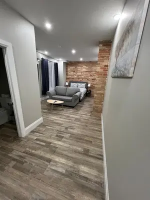 a living room with a couch and a brick wall at ENTIRE BACHELOR UNIT EN-SUITE ACROSS FROM GOOGLE - br2 in Kitchener