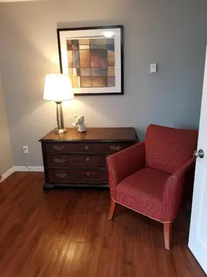 a living room with a red chair and a dresser at The Rosehall PEC Waterfront Stay in Wellington