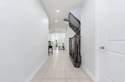 a hallway with white walls and a staircase in a house at Beautiful 4 bed, 3 master bedrooms-pvt washrooms in Brampton