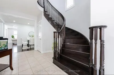 a spiral staircase in a living room with a table at Beautiful 4 bed, 3 master bedrooms-pvt washrooms in Brampton