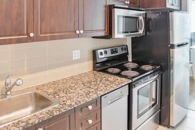 a kitchen with a stove and a stainless steel refrigerator at Panorama Luxe Suites - Prime Downtown Location in Toronto