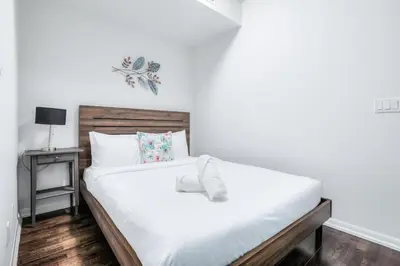 a bedroom with a white bed with a wooden headboard at Panorama Luxe Suites - Prime Downtown Location in Toronto