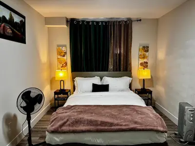 a bedroom with a large bed with two lamps and a fan at Gateway to Serenity-Welcome home in London