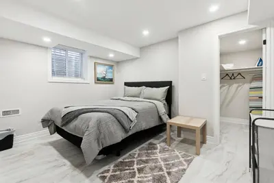 a white bedroom with a bed and a table at Baker Hill Executive Suite 2 Br Basement Apartment with Full Kitchen and Bath in Stouffville