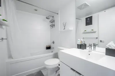 a white bathroom with a tub and a toilet and a sink at Apartment in Downtown Toronto in Toronto