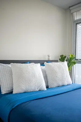 a blue bed with four white pillows on it at Apartment in Downtown Toronto in Toronto