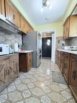 a large kitchen with wooden cabinets and a refrigerator at Cozy Stay, Self Check-In with Parking available upon request in Toronto