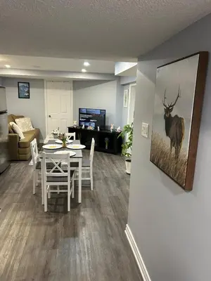 a living room with a table and a painting of a deer at Beautiful and cozy unit in Mississauga