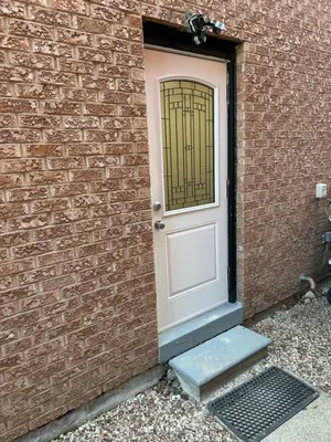 a white door on a brick wall with a stairs at Beautiful and cozy unit in Mississauga