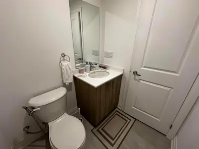 a bathroom with a toilet and a sink with a mirror at Brand New 2 Storey Unit With A Free Parking Space in Richmond Hill