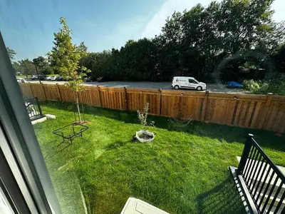 a yard with a fence and a white car in it at Brand New 2 Storey Unit With A Free Parking Space in Richmond Hill