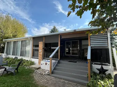 a small house with a porch and a deck at Sherkton Shore Resort in Port Colborne