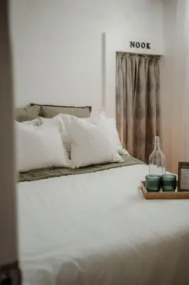 a bed with white pillows and a bottle on a tray at The Barrie Nook in Barrie