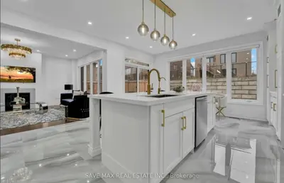 a white kitchen with a sink and a living room at The Rustic Pearl in East Gwillimbury