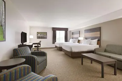 a hotel room with a bed and a couch and chairs at Days Inn & Suites by Wyndham Lindsay in Lindsay
