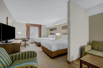 a hotel room with two beds and a flat screen tv at Days Inn & Suites by Wyndham Lindsay in Lindsay