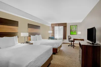 a hotel room with two beds and a flat screen tv at Days Inn & Suites by Wyndham Lindsay in Lindsay