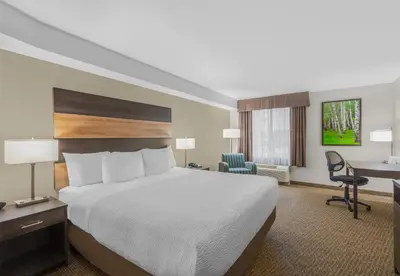 a hotel room with a bed and a desk at Days Inn & Suites by Wyndham Lindsay in Lindsay