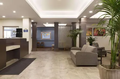 a lobby with a waiting area with chairs and plants at Days Inn & Suites by Wyndham Lindsay in Lindsay