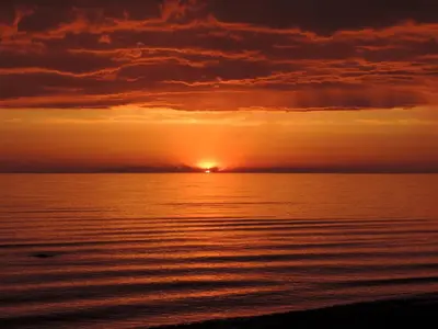 a sunset over the ocean with the sun setting at Woodland Cedars Family Cottage Resort in Wasaga Beach