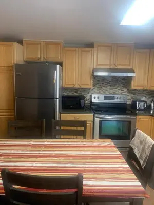 a kitchen with a table and a stainless steel refrigerator at Woodland Cedars Family Cottage Resort in Wasaga Beach