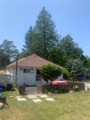 a house with a fence in front of a yard at Woodland Cedars Family Cottage Resort in Wasaga Beach