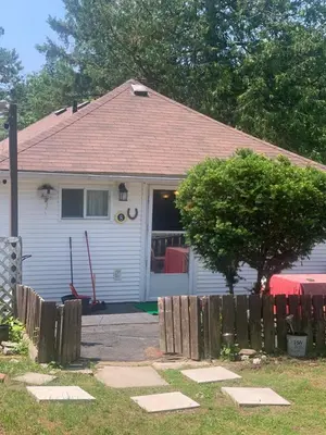 a white house with a fence in front of it at Woodland Cedars Family Cottage Resort in Wasaga Beach