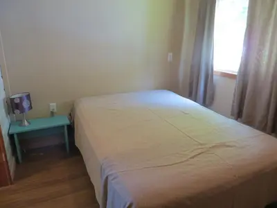 a bedroom with a bed and a table and a window at Woodland Cedars Family Cottage Resort in Wasaga Beach