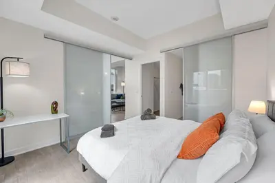 a bedroom with a large white bed with orange pillows at Luxe 5bd Unit sleeps 11 - Hospitals MTCC TTC ACC in Toronto