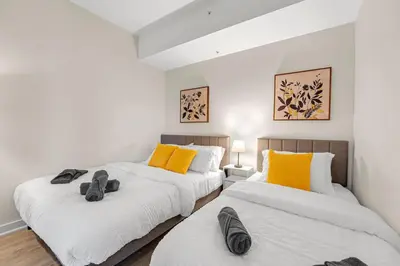 two beds in a room with white and yellow pillows at Luxe 5bd Unit sleeps 11 - Hospitals MTCC TTC ACC in Toronto