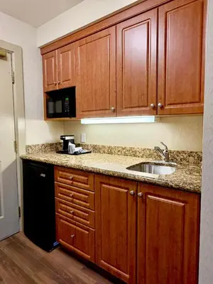a kitchen with wooden cabinets and a sink at Waterloo Suites Hotel, Trademark Collection by Wyndham in Waterloo