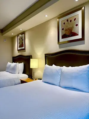 a hotel room with two beds with white pillows at Waterloo Suites Hotel, Trademark Collection by Wyndham in Waterloo