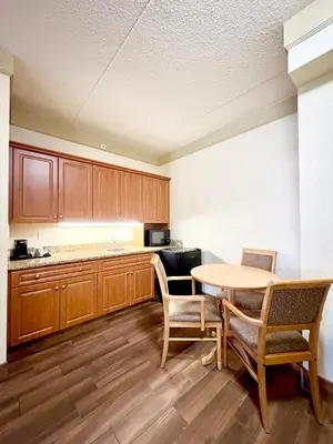 a kitchen with wooden cabinets and a table and chairs at Waterloo Suites Hotel, Trademark Collection by Wyndham in Waterloo
