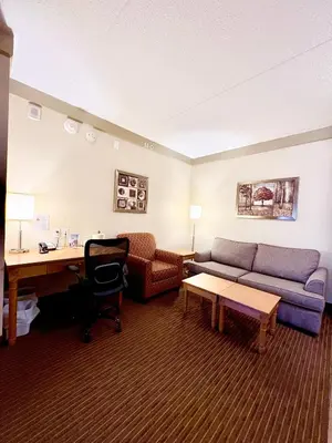 a hotel room with a couch and a desk at Waterloo Suites Hotel, Trademark Collection by Wyndham in Waterloo