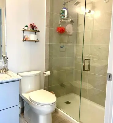 a bathroom with a toilet and a glass shower at Modern & Stylish Condo Downtown in Mississauga