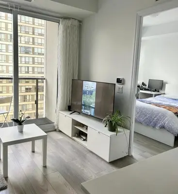 a living room with a television and a bed at Modern & Stylish Condo Downtown in Mississauga