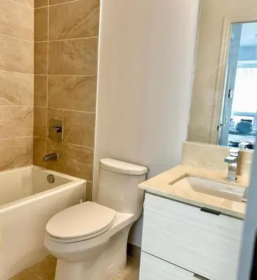 a white bathroom with a toilet and a sink at Modern & Stylish Condo Downtown in Mississauga