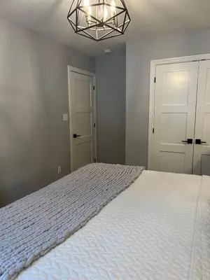 a bedroom with a white bed and a chandelier at Wiley Woods Cottage in Minden