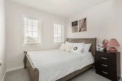 a white bedroom with a bed with white sheets and pillows at The Mt Pleasant Residence - 'Your Cozy Away-Home' in Brampton