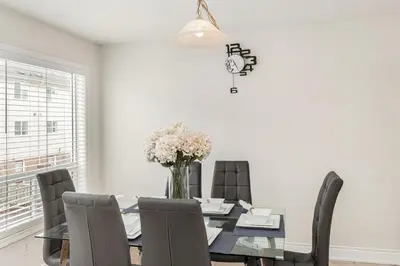 a dining room with a table with chairs and a vase of flowers at The Mt Pleasant Residence - 'Your Cozy Away-Home' in Brampton