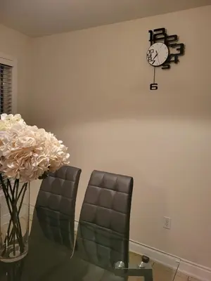 a dining room with two chairs and a clock on the wall at The Mt Pleasant Residence - 'Your Cozy Away-Home' in Brampton