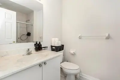 a white bathroom with a toilet and a sink at The Mt Pleasant Residence - 'Your Cozy Away-Home' in Brampton