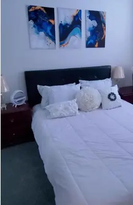 a bedroom with a white bed with pictures on the wall at The Mt Pleasant Residence - 'Your Cozy Away-Home' in Brampton